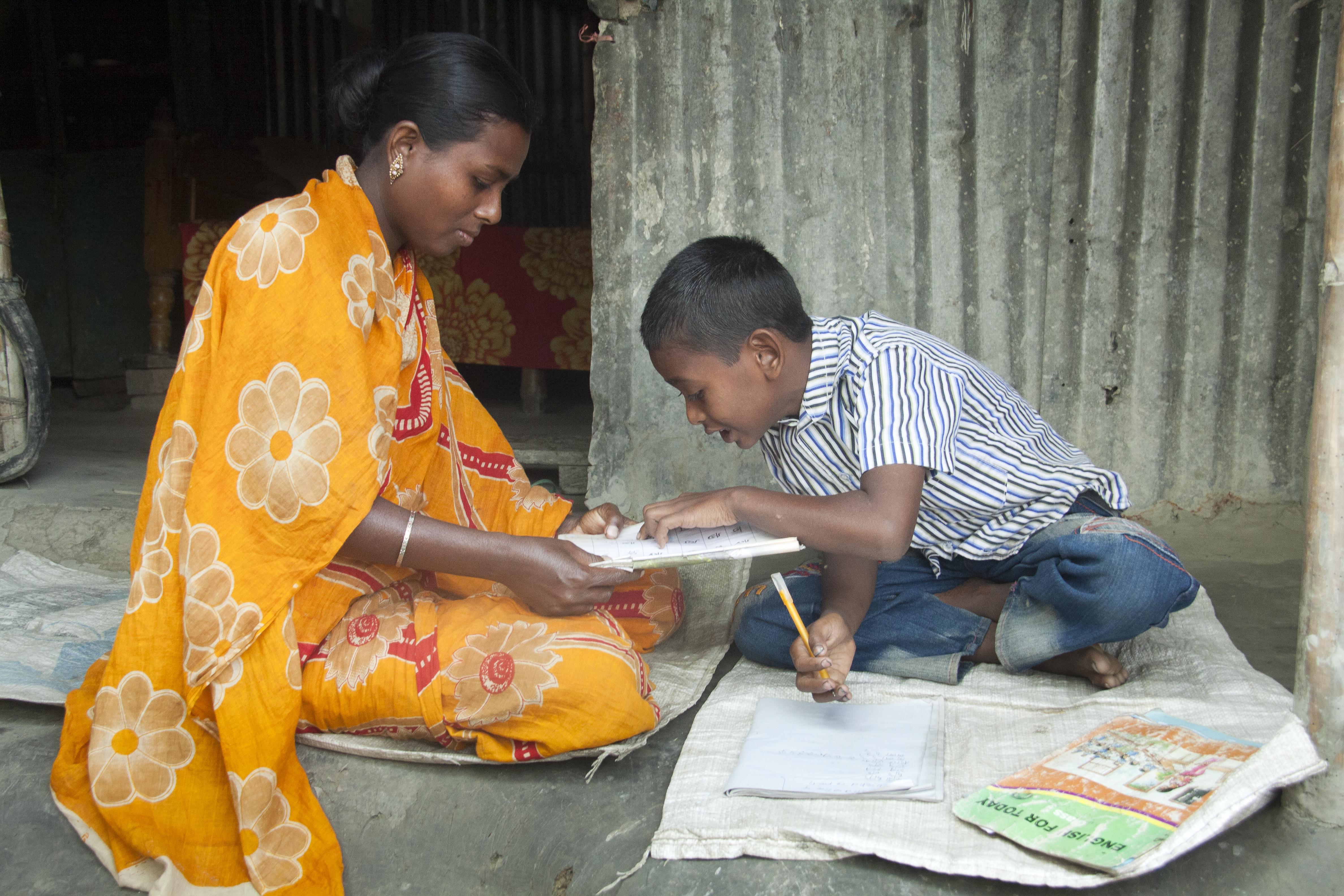 Halima Khatun helping her son with homework, Netrakona, Bangladesh. Photo: UN Women/Saikat Mojumder