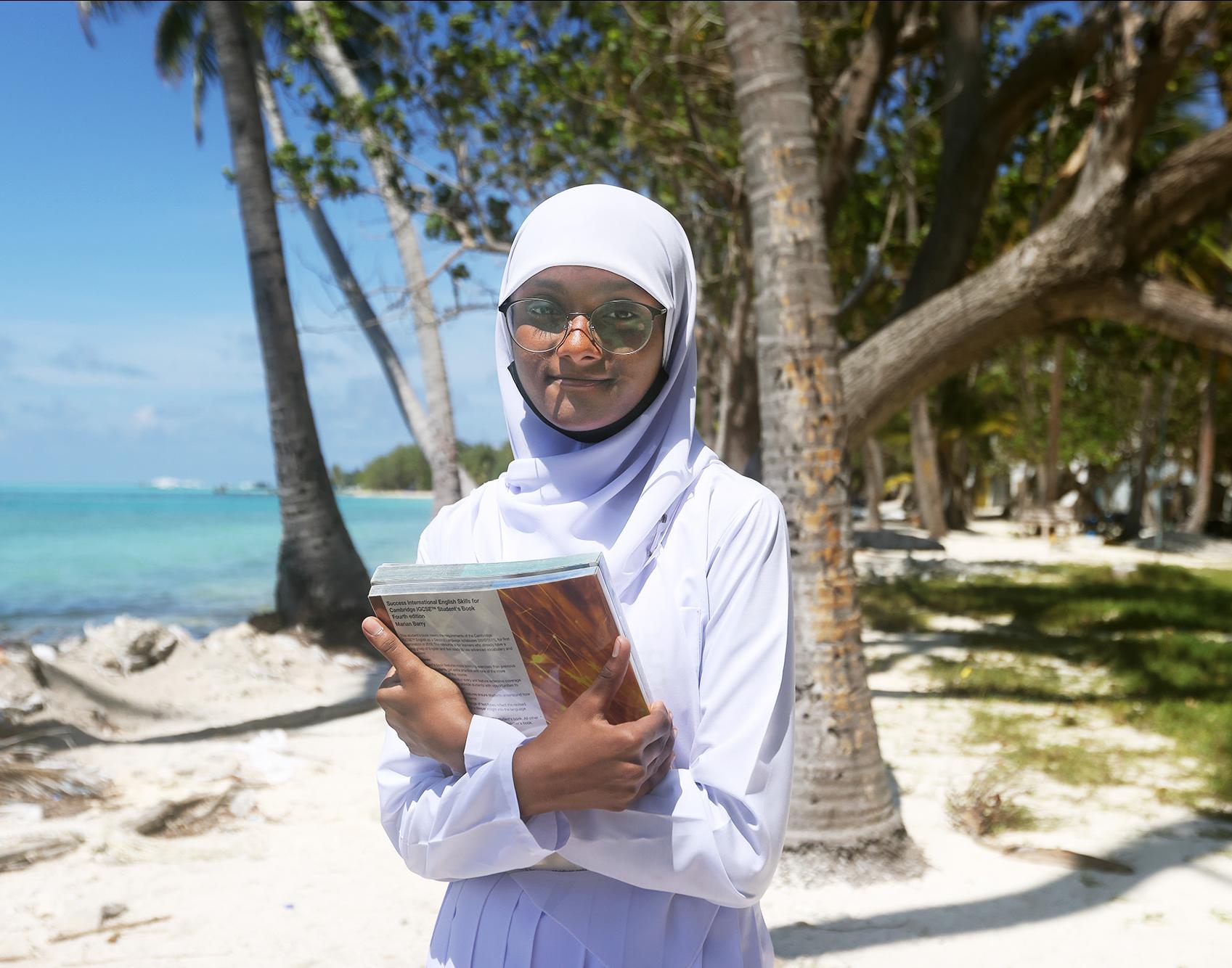 Fathimath Maoona binth Anis, 15, at the beach right in front of their school in Dhiffushi, Maldives. Photo: UNICEF/Ashwa Faheem